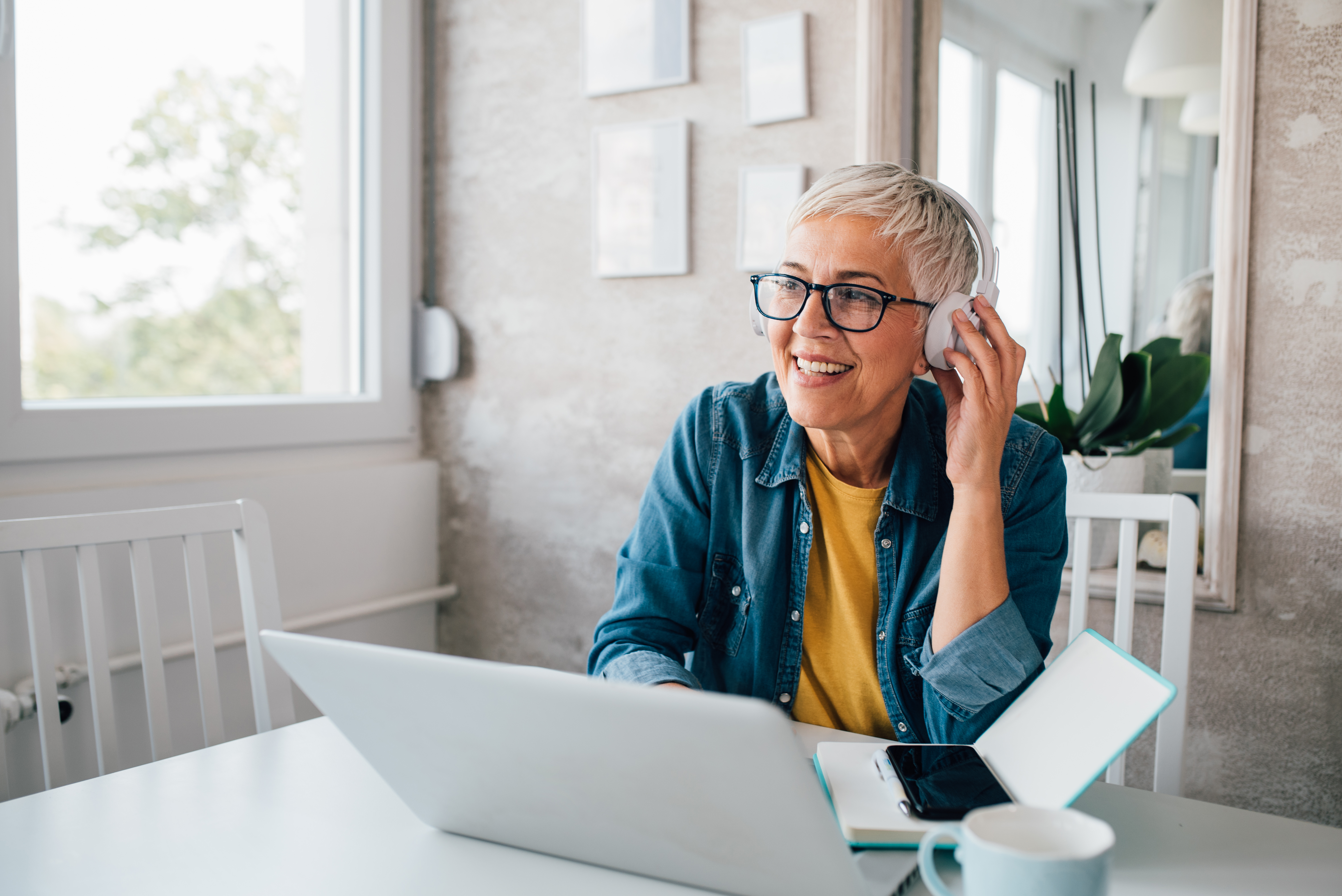 Smiling woman with headphones on, using laptop.