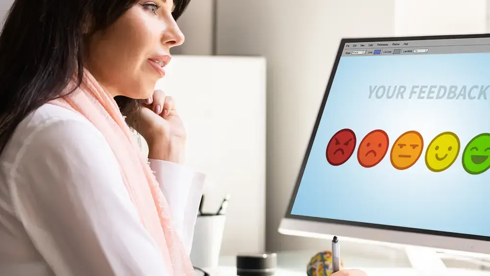 Une femme donne son avis sur un ordinateur à l'aide de smileys.