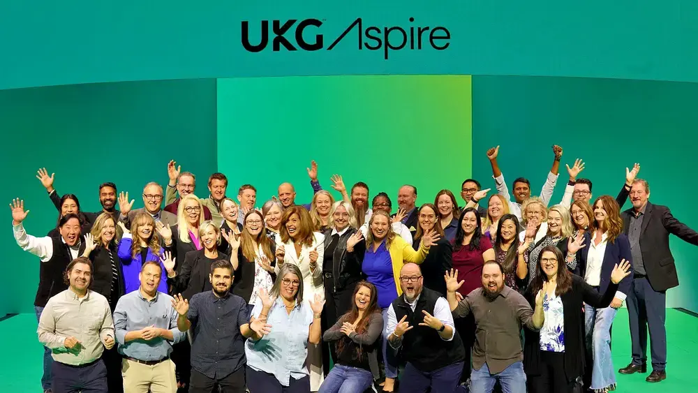 Foule joyeuse avec le logo UKG Aspire.