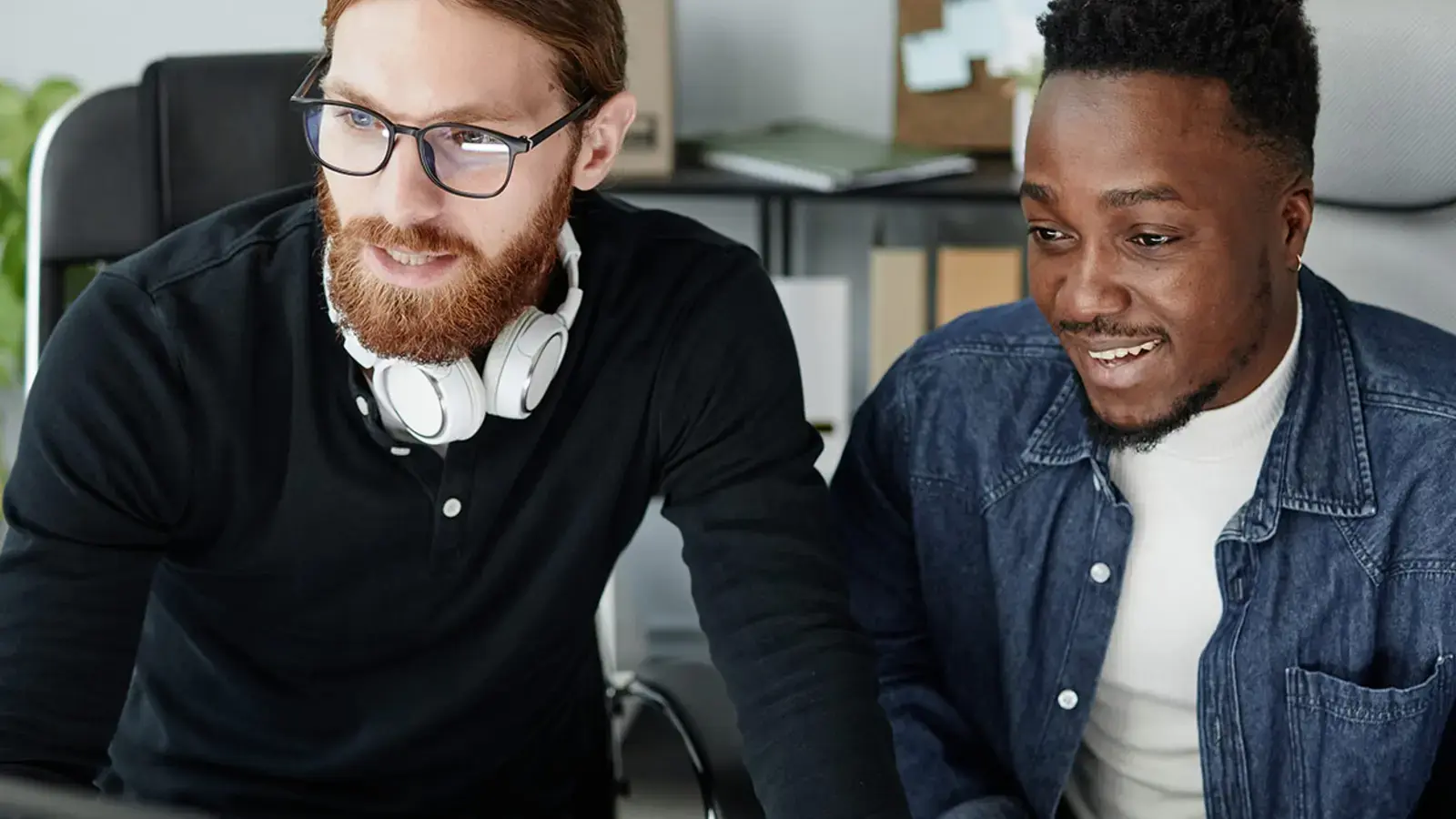 Deux collègues collaborent sur un projet, en utilisant des ordinateurs au bureau.