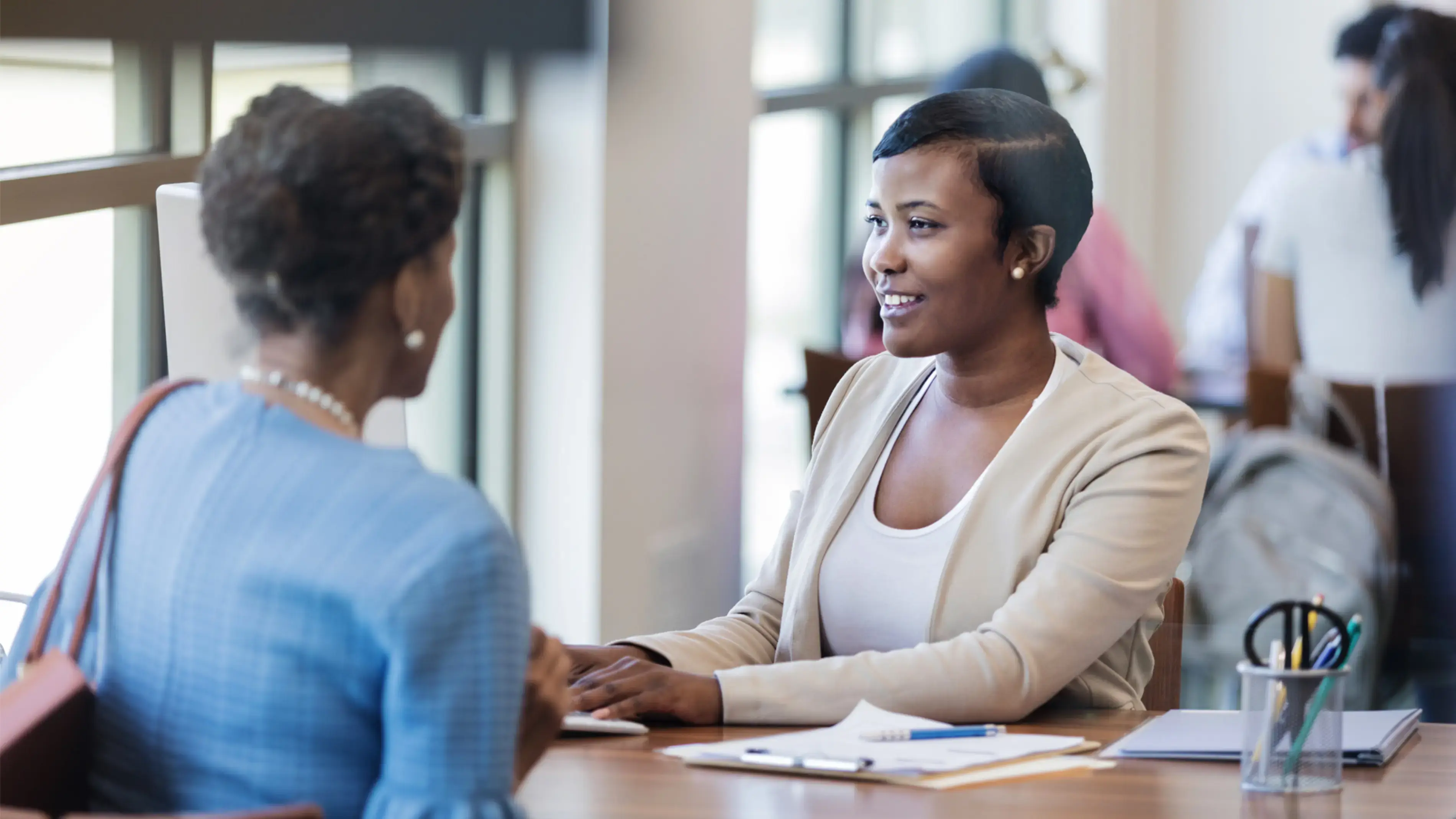 Deux femmes en pleine conversation autour d'une table ronde, dans un environnement de travail.
