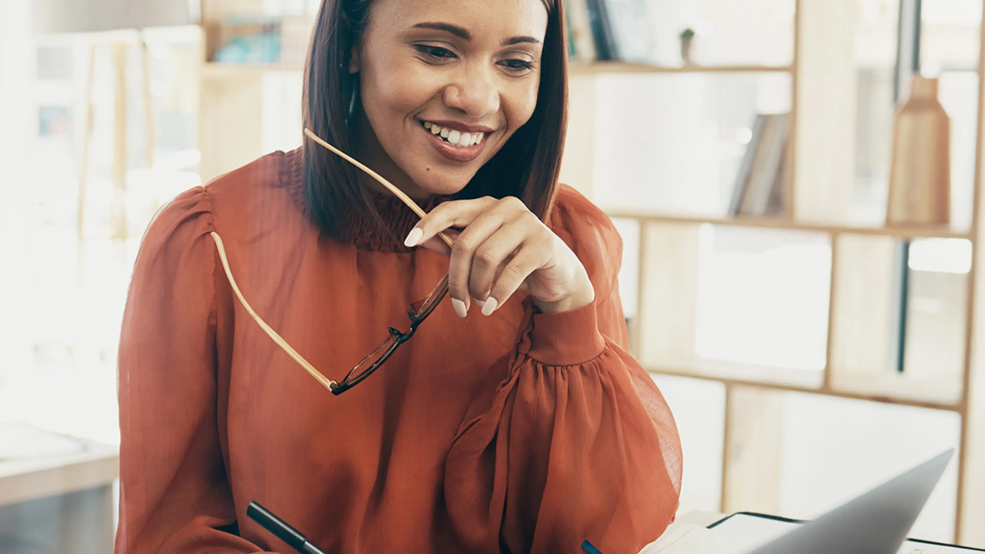Une femme souriante travaille sur un ordinateur portable au bureau.