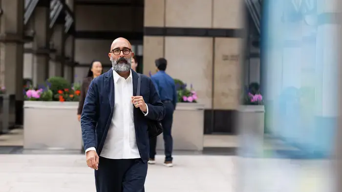 Un homme en costume passe devant un immeuble de bureaux.