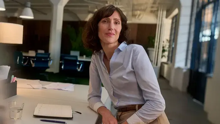 Une femme souriante appuyée sur un bureau dans un bureau.