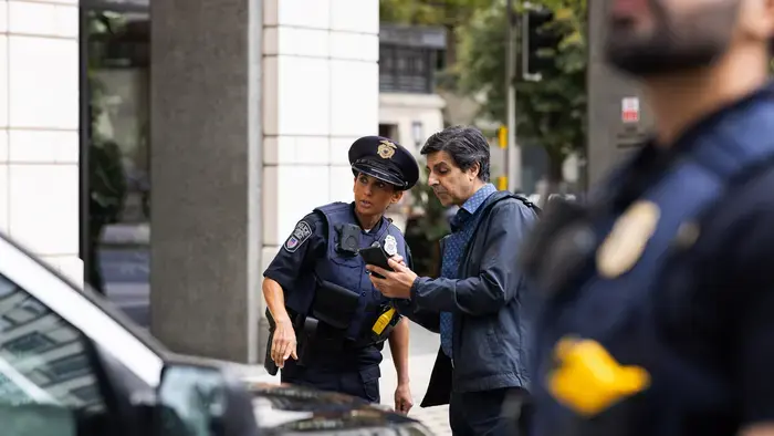 Deux policiers et un homme examinent un smartphone.