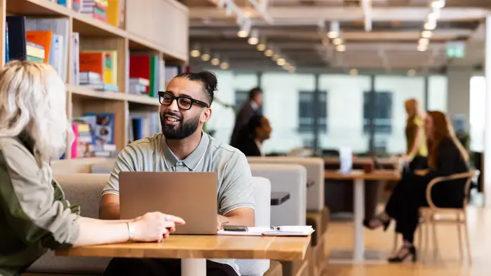 Deux collègues collaborent à une table en utilisant un ordinateur portable.