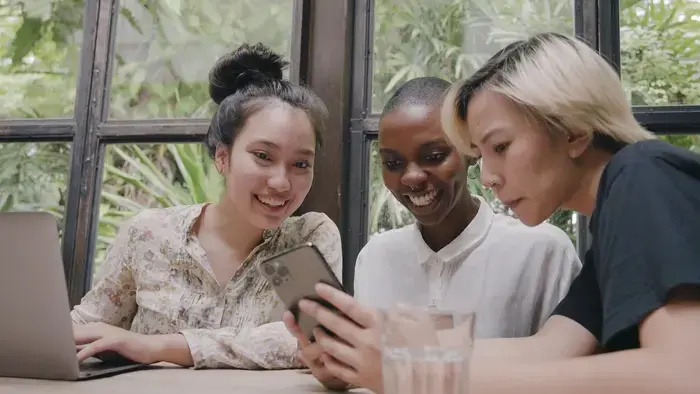 Trois collègues regardent un smartphone près d'un ordinateur portable.