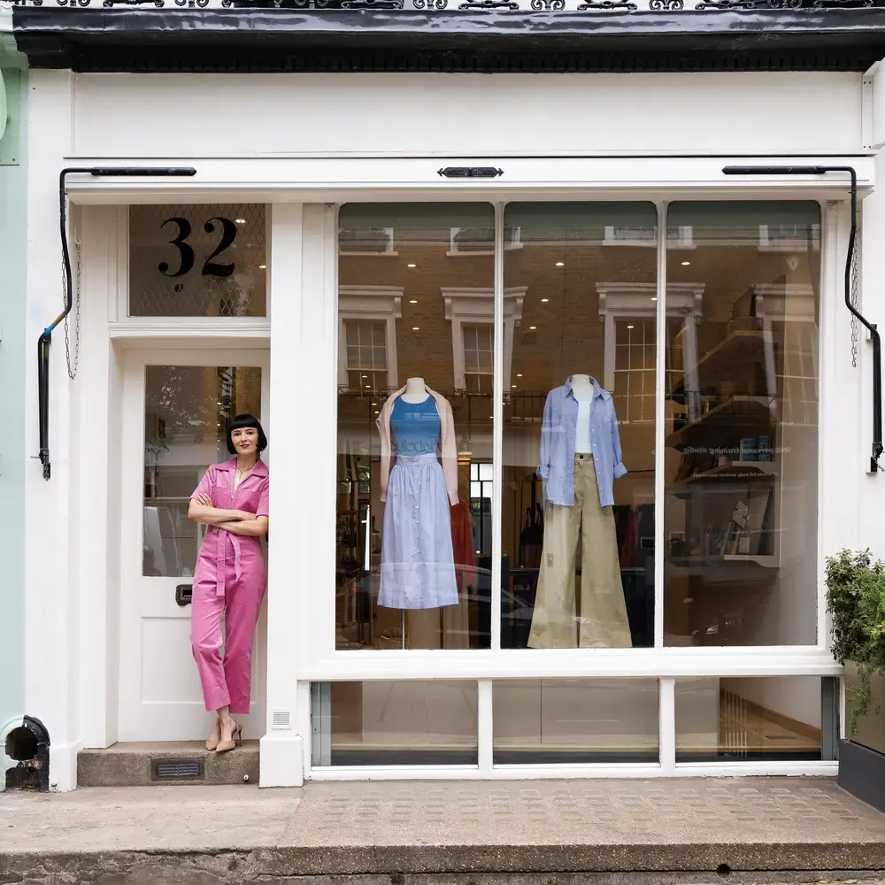 Une femme se tient devant une boutique de vêtements.